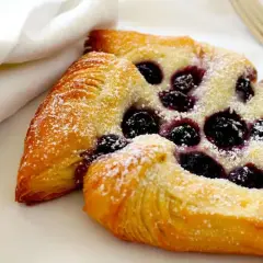 Pyszne ciasto drożdżowe z jagodami, posypane cukrem pudrem. Idealne na deser.