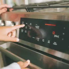 Dłoń ustawia temperaturę 400°F na piekarniku, przygotowując się do wekowania w piekarniku.