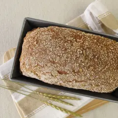 Gotowy do pieczenia chleb orkiszowy na drożdżach w keksówce, posypany ziarnami. Idealny przepis na zdrowe śniadanie.