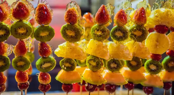 Szklane owoce, jak na przykładzie tego przepisu, to pyszne i kolorowe przekąski. Truskawki, kiwi i ananas w karmelu.