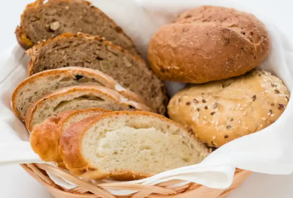 Koszyk z różnymi rodzajami chleba i bułek. Dowiedz się, jak odświeżyć chleb, by znów był pyszny.